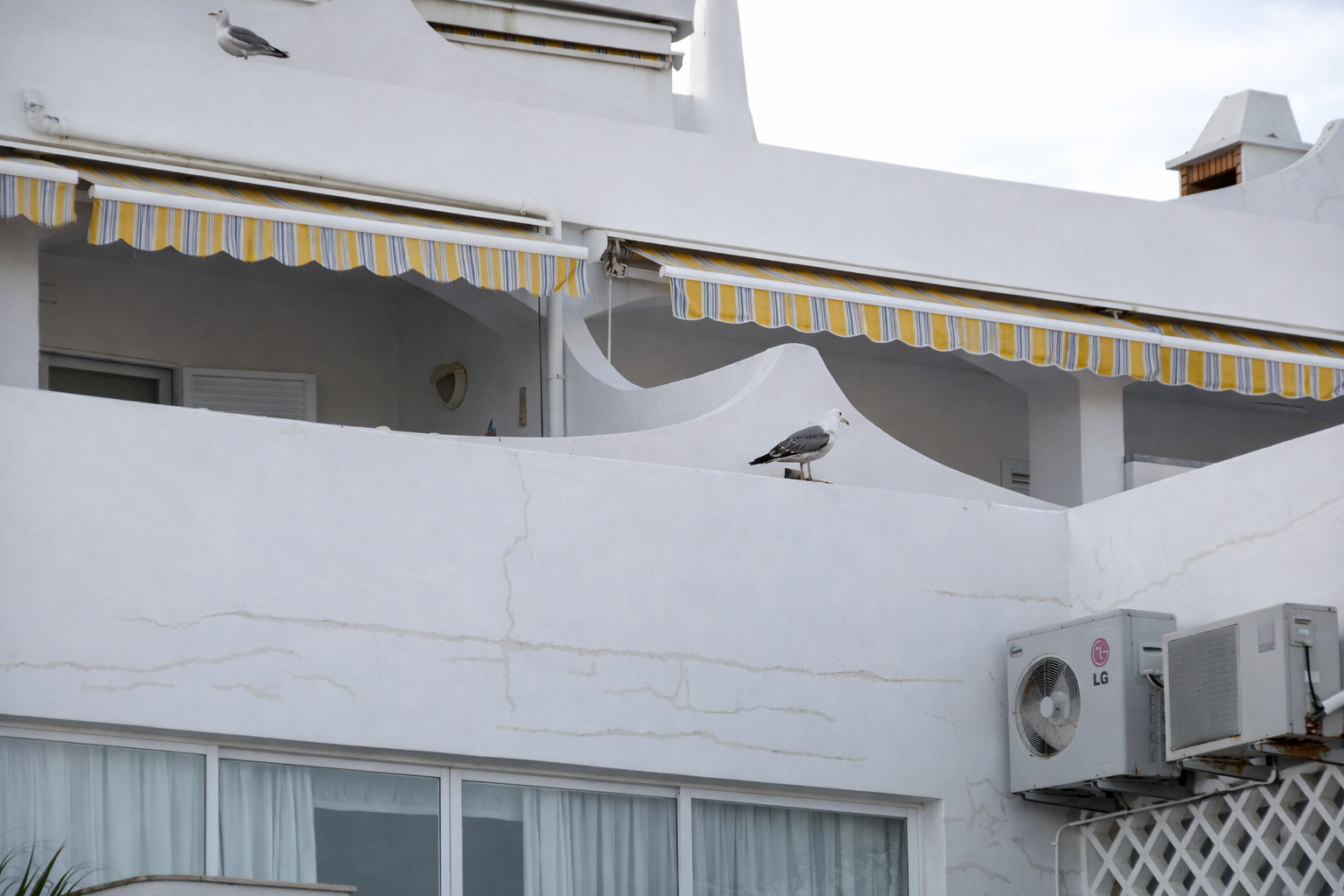 Edifício mediterrânico com gaivotas e toldos