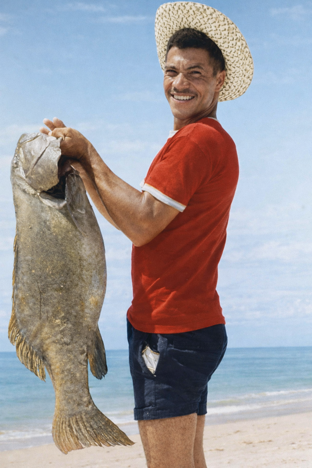 Homem na praia com grande peixe