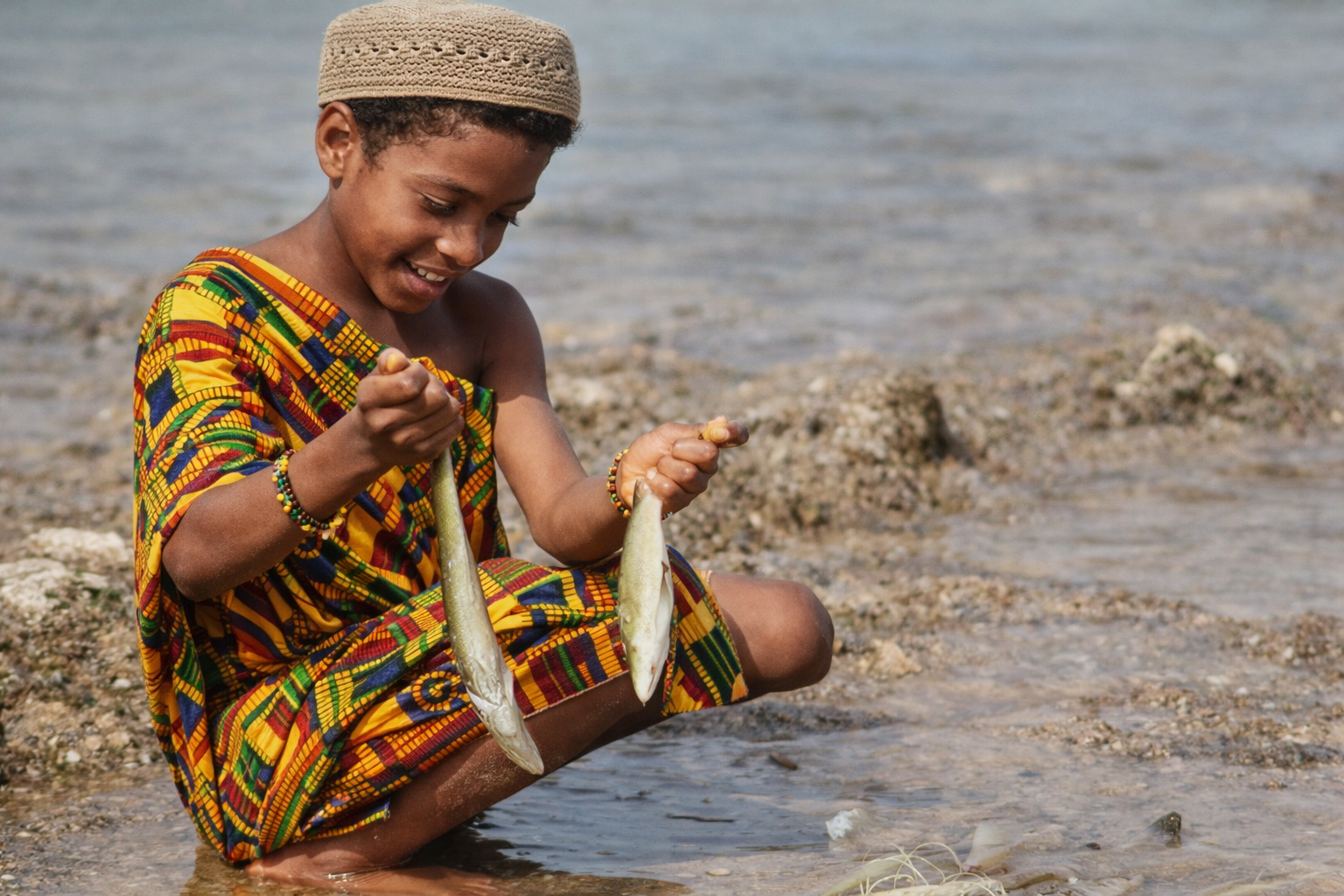 Menino com peixe à beira-mar