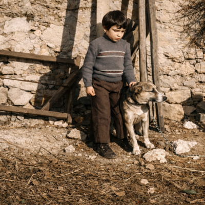 Menino e cão em cenário rústico