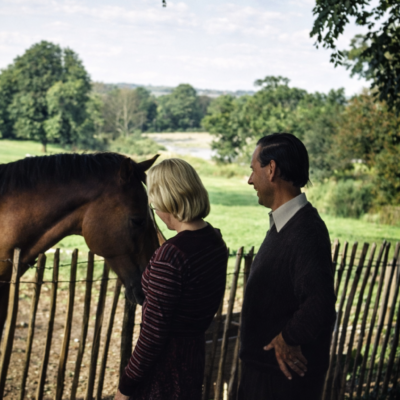 Casal observa cavalo na paisagem campestre