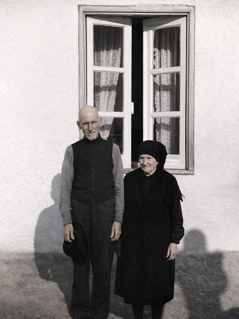 Casal envelhecido em frente à casa branca