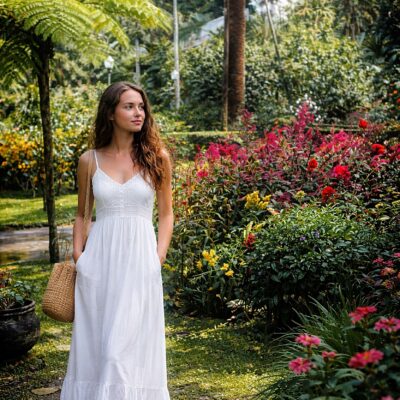Mulher em vestido branco no jardim tropical