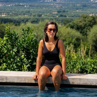 Mulher à beira da piscina ao sol
