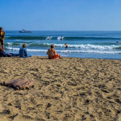 Praia ensolarada com surfistas ao longe